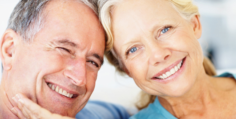 Closeup portrait of a smiling retired couple against bright background